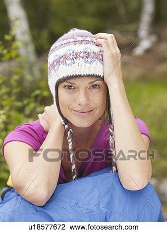 Stock Image - Woman sitting with a sleeping bag around waist smiling.. Fotosearch