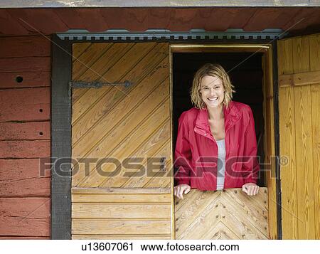 Stock Image - Woman standing in a doorway smiling.. Fotosearch