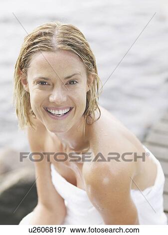 Woman wearing towel sitting on dock smiling. View Large Photo Image Stock Photo - Woman wearing towel sitting on dock smiling.. Fotosearch