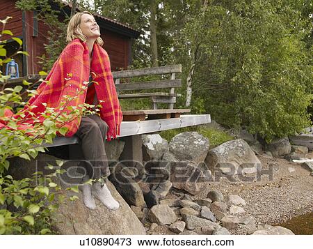 Woman with blanket wrapped around her sitting on dock smiling. View Large Photo Image Stock Image - Woman with blanket wrapped around her sitting on dock smiling.. Fotosearch