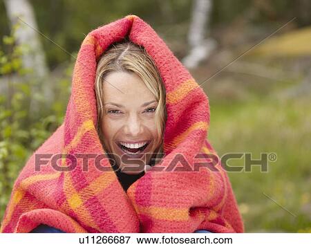 Stock Photo - Woman with blanket wrapped around her laughing.. Fotosearch