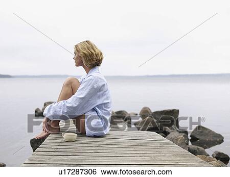 Woman with eyes closed sitting on a dock with a mug. View Large Photo Image Stock Photograph - Woman with eyes closed sitting on a dock with a mug.. Fotosearch