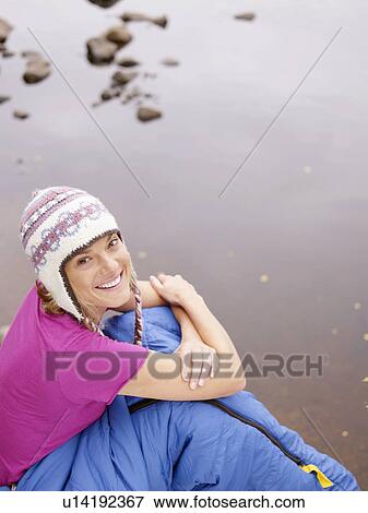 Woman with sleeping bag wrapped around her waist smiling by water. View Large Photo Image Stock Photo - Woman with sleeping bag wrapped around her waist smiling by water.. Fotosearch