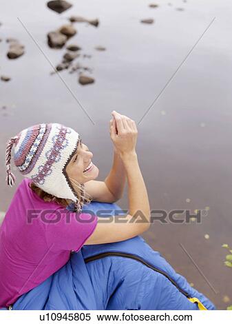 Woman with sleeping bag wrapped around her waist smiling by water. View Large Photo Image Stock Photography - Woman with sleeping bag wrapped around her waist smiling by water.. Fotosearch