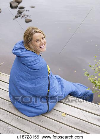 Woman wrapped in sleeping bag sitting on dock smiling. View Large Photo Image Stock Photography - Woman wrapped in sleeping bag sitting on dock smiling.. Fotosearch