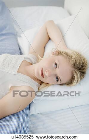 Stock Photography - Portrait of a woman laying on a bed.. Fotosearch