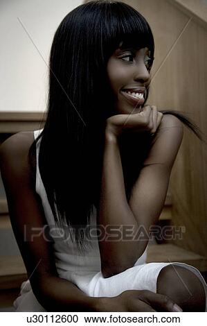 Stock Image - Portrait of a woman sitting on stairs. Fotosearch