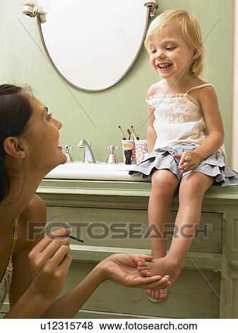 Stock Photo - Mother and daughter applying makeup.. Fotosearch