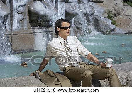 businessman sitting by fountain with coffee to go wearing sunglasses View Large Photo Image Stock Image - businessman sitting by fountain with coffee to go wearing sunglasses. Fotosearch
