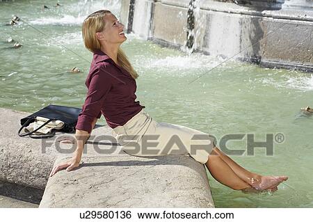 Businesswoman sitting on fountain feet in fountain laughing. View Large Photo Image Stock Photograph - Businesswoman sitting on fountain feet in fountain laughing.. Fotosearch