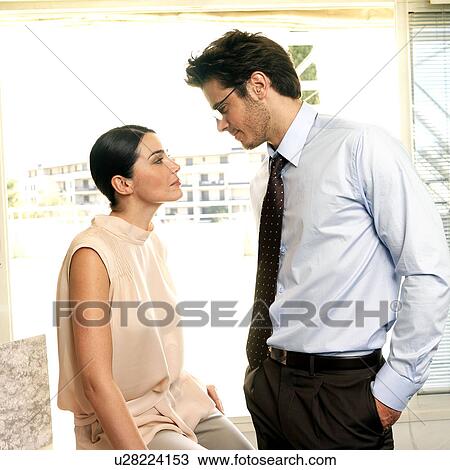 Stock Image - Couple facing each other in office. Fotosearch