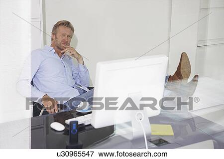 Man at computer relaxing with feet on desk with reflections. View Large Photo Image Stock Photo - Man at computer relaxing with feet on desk with reflections.. Fotosearch