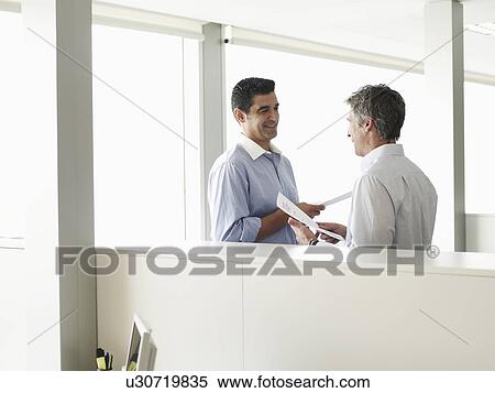Stock Photography - Two businessmen talking in office. Fotosearch