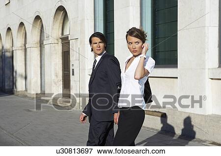 Stock Photo - young businessman and woman walking on city street. Fotosearch