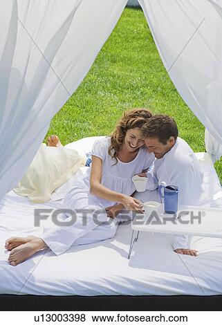 Couple having breakfast on bed in garden View Large Photo Image Stock Photo - Couple having breakfast on bed in garden. Fotosearch