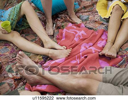 Stock Image - Four pair of bare feet on blankets. Fotosearch