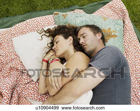 Stock Photo - Man and woman sleeping on blanket. Fotosearch