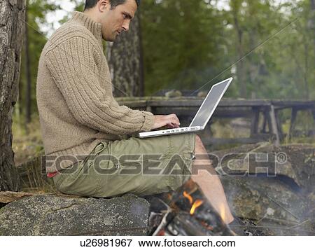 Man on laptop by fire pit. View Large Photo Image Stock Photo - Man on laptop by fire pit.. Fotosearch