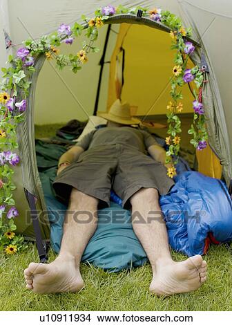 Picture - Man sleeping in tent with hat on face. Fotosearch