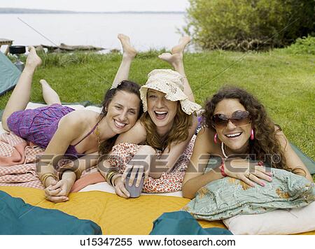 Stock Photography - Three women laying on blankets smiling. Fotosearch