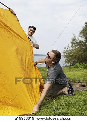Stock Photo - Two men setting up a tent together. Fotosearch