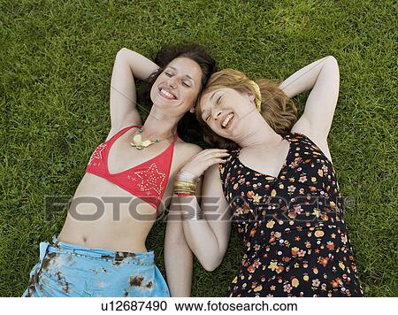 Stock Image - Two women laying on grass smiling. Fotosearch