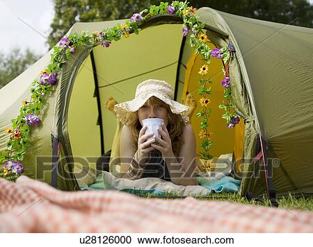 Stock Image - Woman lying inside tent looking out . Fotosearch