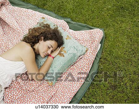 Stock Image - Woman sleeping on blanket outside. Fotosearch