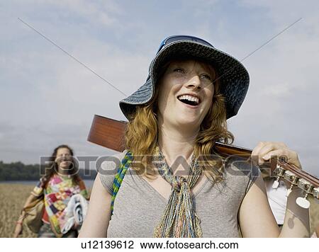 Woman walking with guitar on shoulder View Large Photo Image Stock Image - Woman walking with guitar on shoulder. Fotosearch