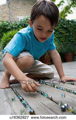 Stock Photo - Portrait of a boy playing marbles.. Fotosearch
