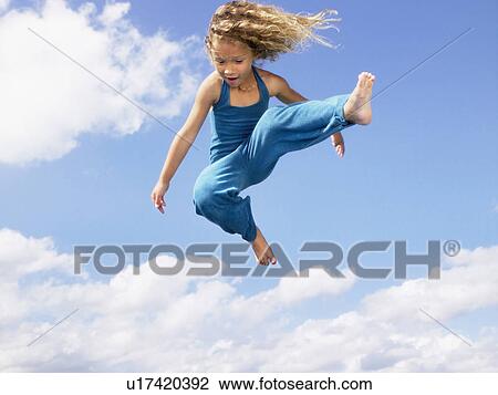 Stock Image - Young girl jumping in the air.. Fotosearch