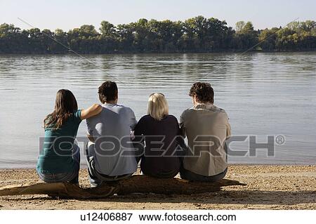 Four friends sitting on log by a lake. View Large Photo Image Stock Photo - Four friends sitting on log by a lake.. Fotosearch