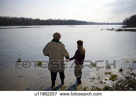 Grandmother and granddaughter (10-12) standing in river, rear view View Large Photo Image Stock Photo - Grandmother and granddaughter (10-12) standing in river, rear view. Fotosearch