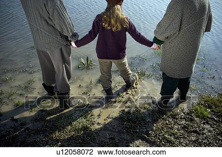 Grandparents holding hands with granddaughter (10-12) by river View Large Photo Image Stock Image - Grandparents holding hands with granddaughter (10-12) by river. Fotosearch
