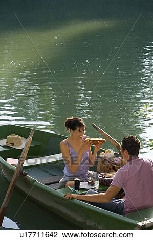 Stock Image - Man and woman having a picnic on boat. Fotosearch