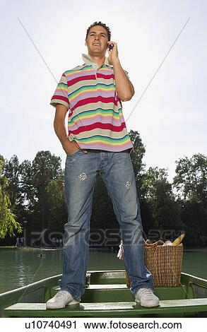 Man with his cell phone standing in a boat View Large Photo Image Stock Image - Man with his cell phone standing in a boat. Fotosearch