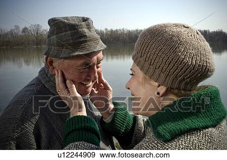 Senior couple by river, woman touching man's face, smiling, close-up View Large Photo Image Stock Photo - Senior couple by river, woman touching man's face, smiling, close-up. Fotosearch