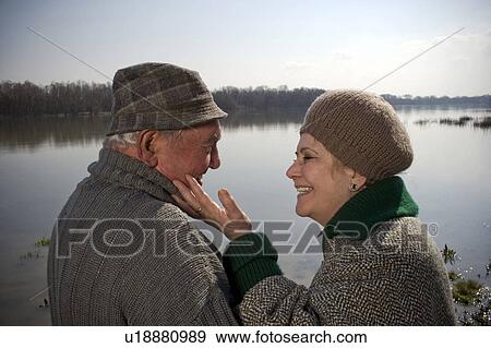 Senior couple by river, woman touching man's face, smiling View Large Photo Image Stock Photo - Senior couple by river, woman touching man's face, smiling. Fotosearch