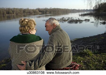 Senior couple sitting on rug by river, rear view, man smiling View Large Photo Image Stock Photo - Senior couple sitting on rug by river, rear view, man smiling. Fotosearch
