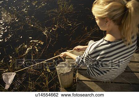 Stock Image - Young Woman by pond with fishing net.. Fotosearch