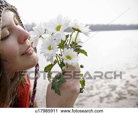 Young woman outdoors holding flowers to nose, eyes closed, close-up View Large Photo Image Stock Image - Young woman outdoors holding flowers to nose, eyes closed, close-up. Fotosearch