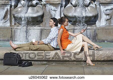 Businessman and woman leaning on each other while sitting on fountain's edge. View Large Photo Image Stock Image - Businessman and woman leaning on each other while sitting on fountain's edge.. Fotosearch