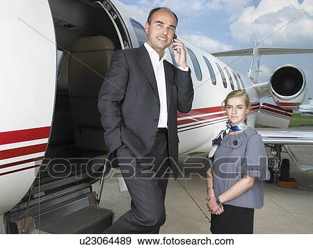 Businessman exiting private jet next to flight attendant. View Large Photo Image Stock Photo - Businessman exiting private jet next to flight attendant.. Fotosearch
