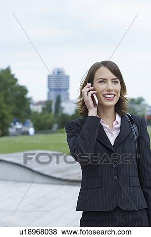 Stock Photo - Businesswoman on the mobile laughing city and park in background.. Fotosearch