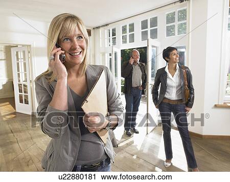 Female real estate agent on phone in show house clients behind. View Large Photo Image Stock Image - Female real estate agent on phone in show house clients behind.. Fotosearch