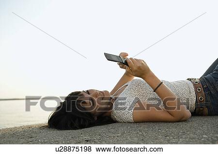 Stock Photo - Girl looking at mobile phone.. Fotosearch