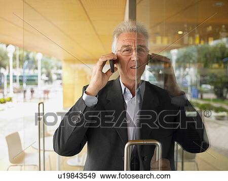 Stock Photo - Man on his cell phone half out a doorway.. Fotosearch