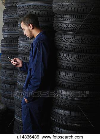 Mechanic standing by stacks of tires View Large Photo Image Stock Photograph - Mechanic standing by stacks of tires. Fotosearch