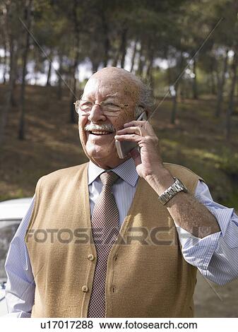 Stock Photo - Senior man using mobile phone, smiling, outdoors. Fotosearch