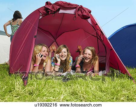 Three girls lying in tent talking on mobile phones View Large Photo Image Stock Photograph - Three girls lying in tent talking on mobile phones. Fotosearch
